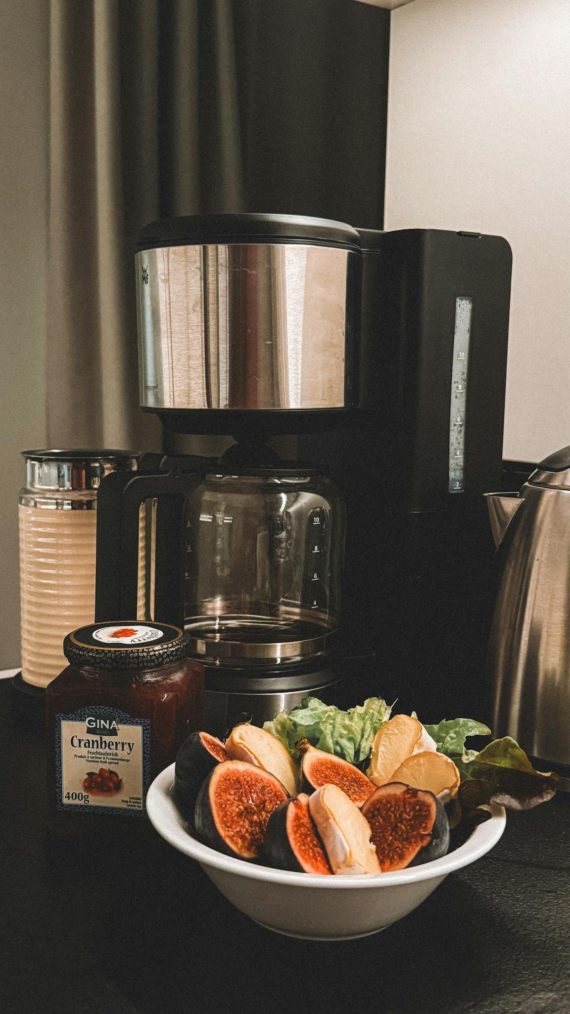 A modern kitchen setup featuring fresh figs, coffee maker, and jam, exuding a warm and inviting mood.