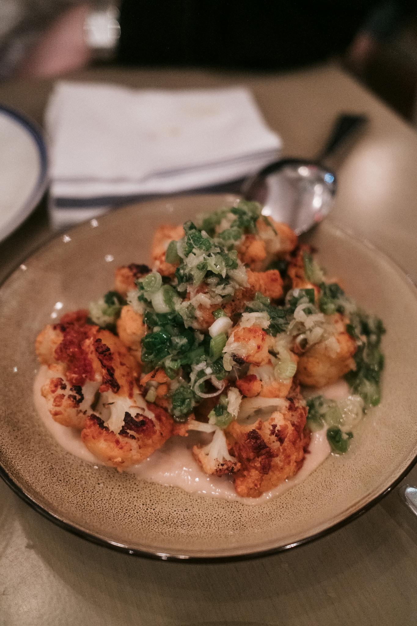 Plate of roasted cauliflower topped with fresh herbs, perfect for a healthy meal.