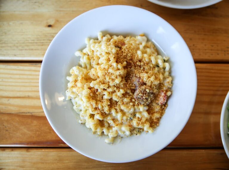 Creamy cottage cheese mac and cheese in a white bowl on a wooden table, overhead view